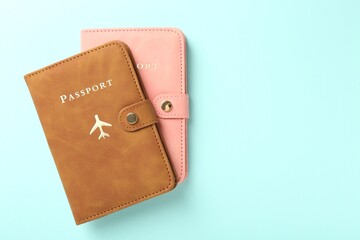 Two passports in bright covers on turquoise background, top view. Space for text