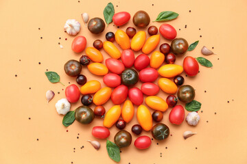 Different fresh tomatoes with basil, garlic and peppercorn on orange background