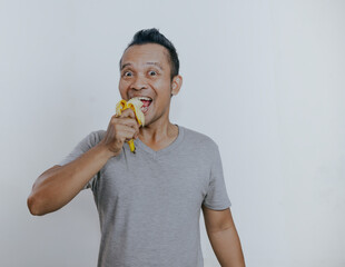 Asian man showing happy expression when eating banana.