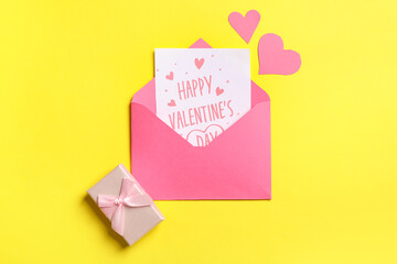 Envelope with gift card, box and paper hearts on yellow background. Valentine's day celebration