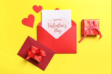 Envelopes with gift card, boxes and paper hearts on yellow background. Valentine's day celebration