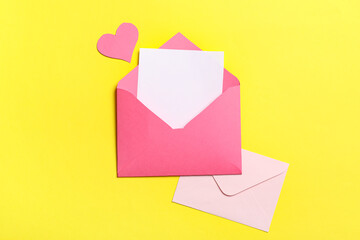 Envelopes with blank card and paper heart on yellow background. Valentine's day celebration