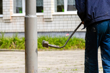 A man is painting a lamppost.