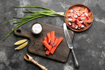 Wooden board and plate with tasty crab sticks on black background © Pixel-Shot