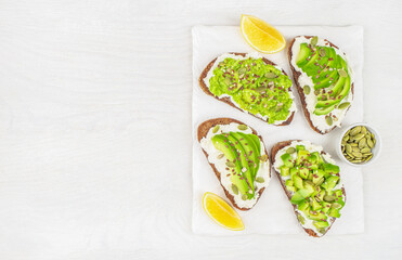 A set of delicious avocado toasts with rye bread, cheese, pumpkin, nut and sesame for breakfast or lunch. Vegetarian food. Vegan menu. top view