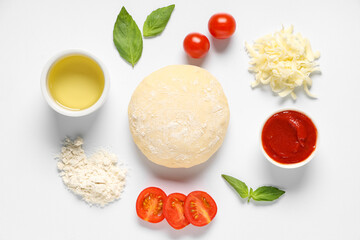 Raw dough and ingredients for preparing pizza on white background