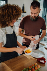 Couple cooking together, whisking eggs in the kitchen