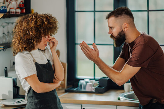 Young couple arguing in kitchen, woman feeling frustrated and annoyed