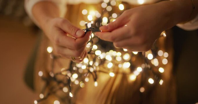 Close-Up of Untangling Christmas Lights by Woman in Home Comfort