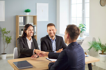 Businessman and colleague shake hands in an office, celebrating a deal and partnership. Handshake signifies teamwork, collaboration, and client agreement in a professional environment.