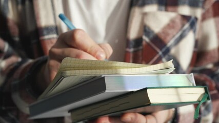 A student sits at a desk and writes in a notepad.
Student learns lessons.
Smart student with a notebook in his hands.
A man takes notes in a notepad.
Man doing homework