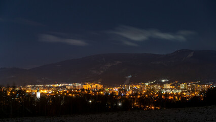 nocna panorama miasta z górami w tle	