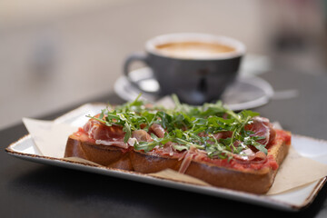 Close-up of a delicious ciabatta sandwich with Jamón Serrano and arugula (rucola). Ideal for food photography, Spanish delicacies, gourmet meals, or Mediterranean-inspired cuisine visuals.
