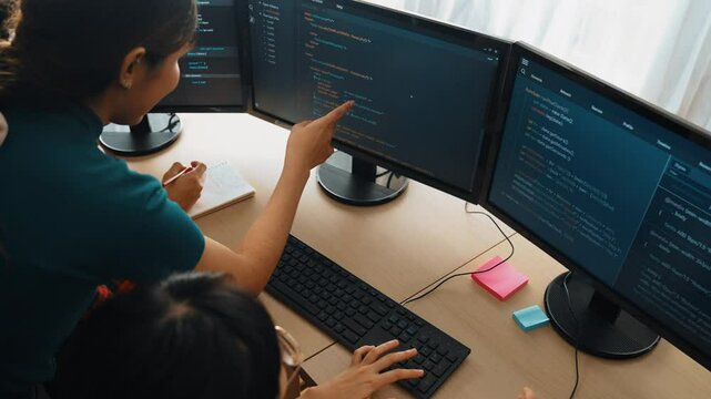 Slow motion back end software developer engineer for computer programming working together on debugging writing computing code, solving complex algorithms display on monitor in office. Burgeoning
