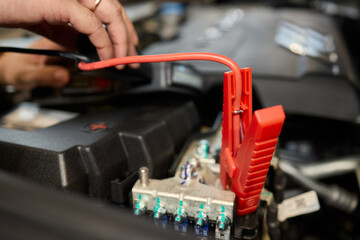 Closeup photo of black car battery connected with jumper cables for repair or recharging
