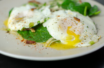 Salad Lyonnaise - Warm bacon & egg salad with spinach and pickled onions, on a black background, breakfast recipe idea