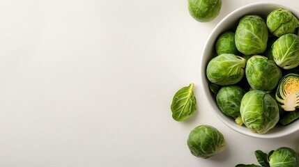 A top view of fresh Brussels sprouts situated in a white bowl on a white background, showcasing their vivid color and adding an aesthetic appeal to the image.