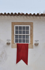 Window with red flag on an old white wall, medieval environment