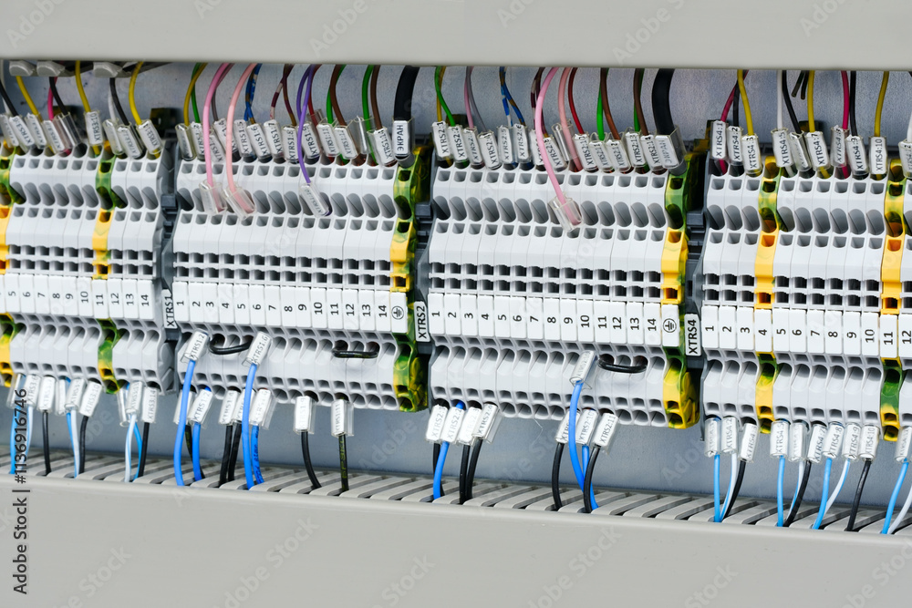 Poster A close up of a power box with many wires and outlets. The box is white and has a red stripe