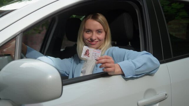 Glad Caucasian vehicle buyer woman owner sit in car smiling lady female showing driver license automobile driving school certificate test drive in city girl businesswoman driver achieve education auto