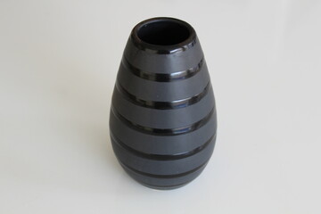 Black ceramic vase with striped design on white background