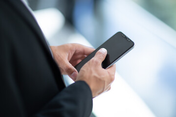 A man is holding a cell phone in his hand. The phone is black and has a screen