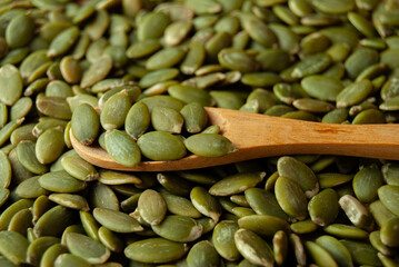 A close-up shot of a wooden spoon filled with piled-up sunflower seeds. 