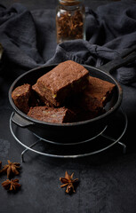 Pieces of baked brownie in a metal black frying pan on the table