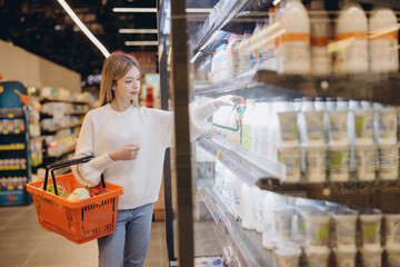 Woman choosing milk in supermarket refrigerated section