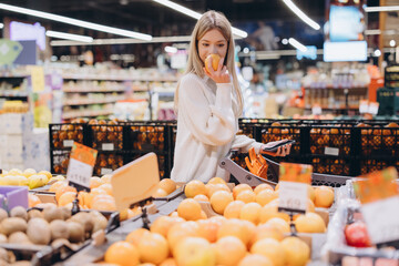 Woman smelling orange while grocery shopping in supermarket