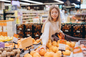 Woman choosing oranges in a supermarket: healthy eating and grocery shopping