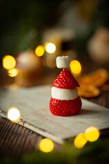 Strawberry and marshmallow in the shape of santa, festive food on table with christmas lights