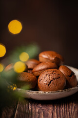 Chocolate muffins in the plate with Christmas lights on dark background 