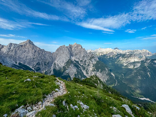 Hiking trail with scenic view of rugged mountain peak Jalovec in wild Julian Alps seen from Triglav...