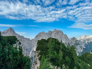 Obraz premium Jagged rock formation with scenic view of rugged mountain peak Prisank in majestic Julian Alps seen from Triglav National Park, Vrsic pass, Slovenia. Wanderlust wild Slovenian Alps. Sharp steep ridges