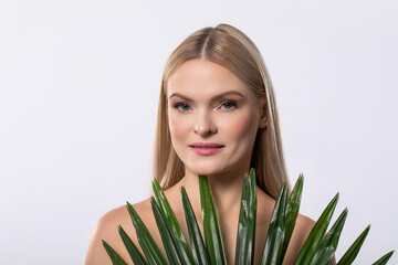 Fototapeta premium A young woman is elegantly holding a thriving green plant set against a pristine white background