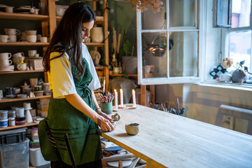 Young pottery workshop owner woman enjoy working with raw clay in studio. Creative artist of potter...