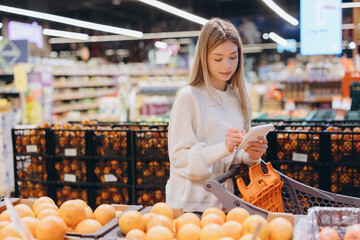 Woman taking notes on notepad while shopping in supermarket