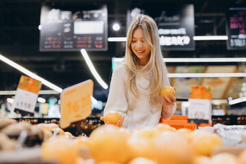 Woman choosing grapefruit in supermarket fruit and vegetable section
