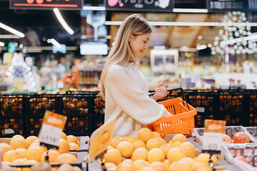 Woman choosing grapefruit in supermarket fruit and vegetable section