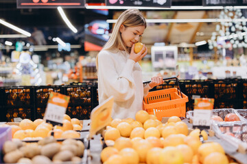 Customer smelling grapefruit choosing fresh fruits in supermarket