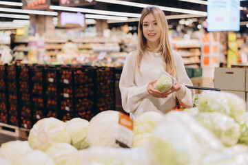 Customer choosing fresh lettuce in supermarket produce section