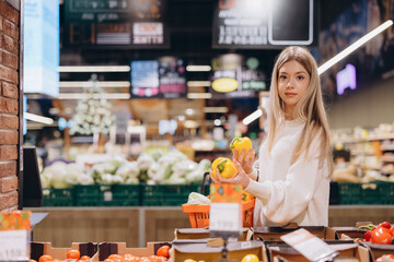 Woman choosing yellow bell peppers in supermarket
