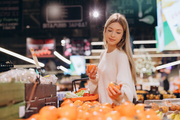 Woman choosing persimmon fruit at the supermarket
