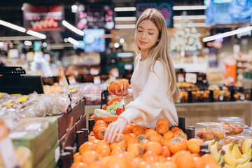 Woman choosing persimmon fruit at the supermarket