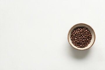 Roasted coffee beans in a rustic bowl on a white background.