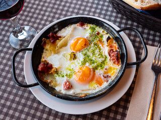 Appetizing Riojan style eggs casserole traditionally prepared with potatoes, bell peppers, sausages and piquant green sauce. Authentic Spanish cuisine