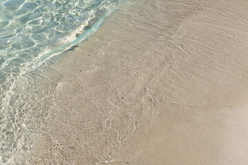 Small water wave in quiet transparent turquoise Mediterranean waters sandy beach in Puglia, Italy