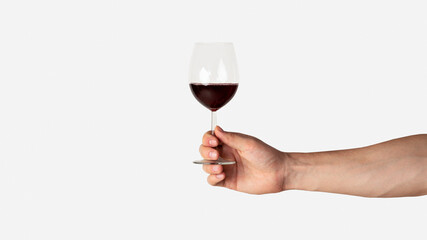 Male hand holding glass of red wine on light background, closeup with copy space. Panorama