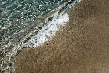 Small water wave in quiet transparent turquoise Mediterranean waters sandy beach in Puglia, Italy